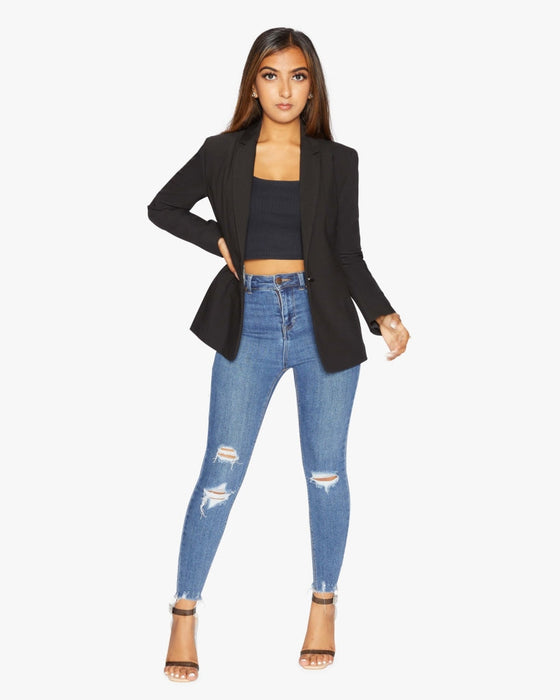 A woman wearing a UK-made black relaxed-fit blazer with an elongated silhouette