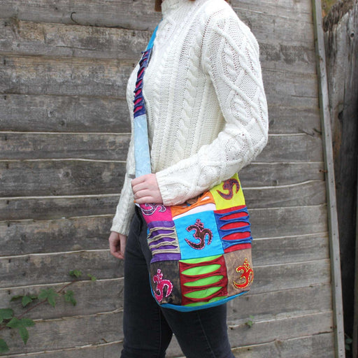 Handcrafted bohemian sling bag with Om symbol embroidery, adjustable strap, and eco-friendly materials.
