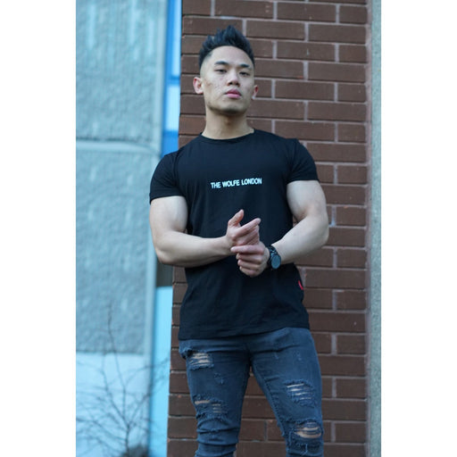 Model wearing slim-fit oversized TWL black tee with bold chest logo

