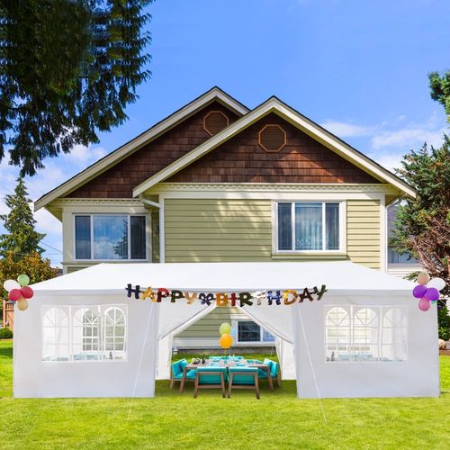 Large white 10x30 outdoor party tent with sidewalls and windows set up in a backyard